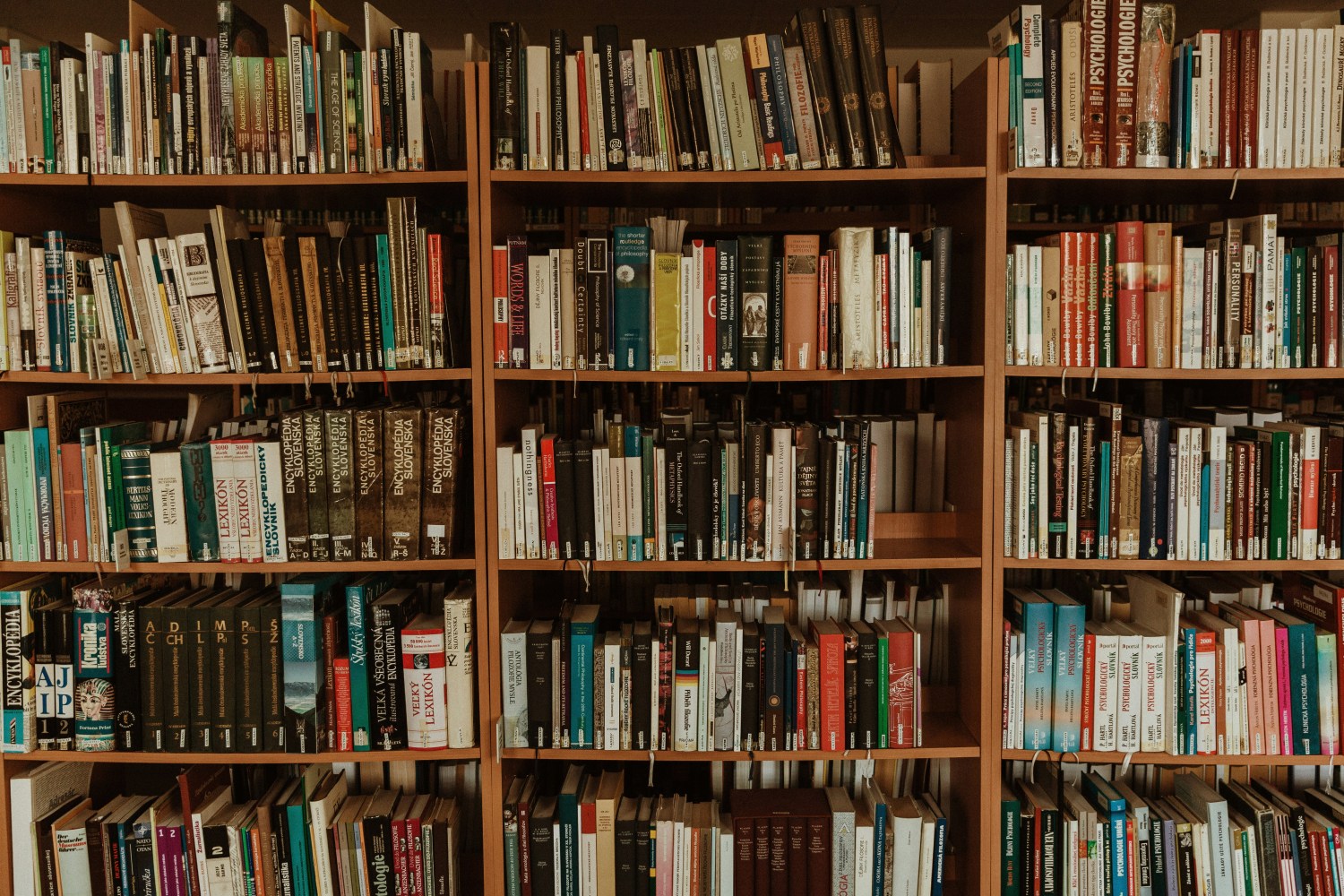 Wooden shelves filled with assorted books in a library setting.